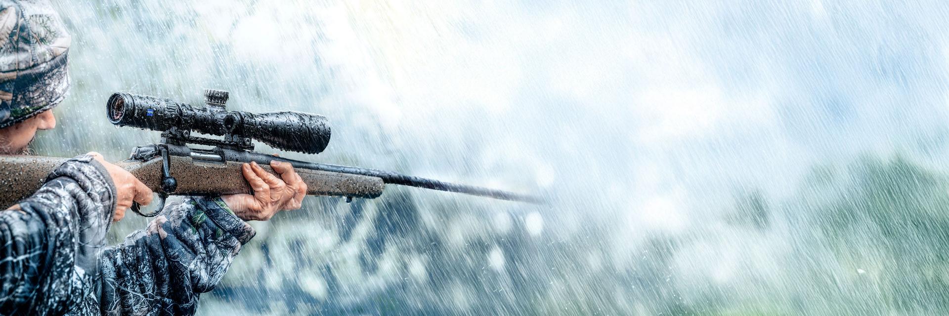 Sunglasses with ZEISS lenses lying on a blue table, reflecting a smiling woman, next to a smartphone and a glass of water.