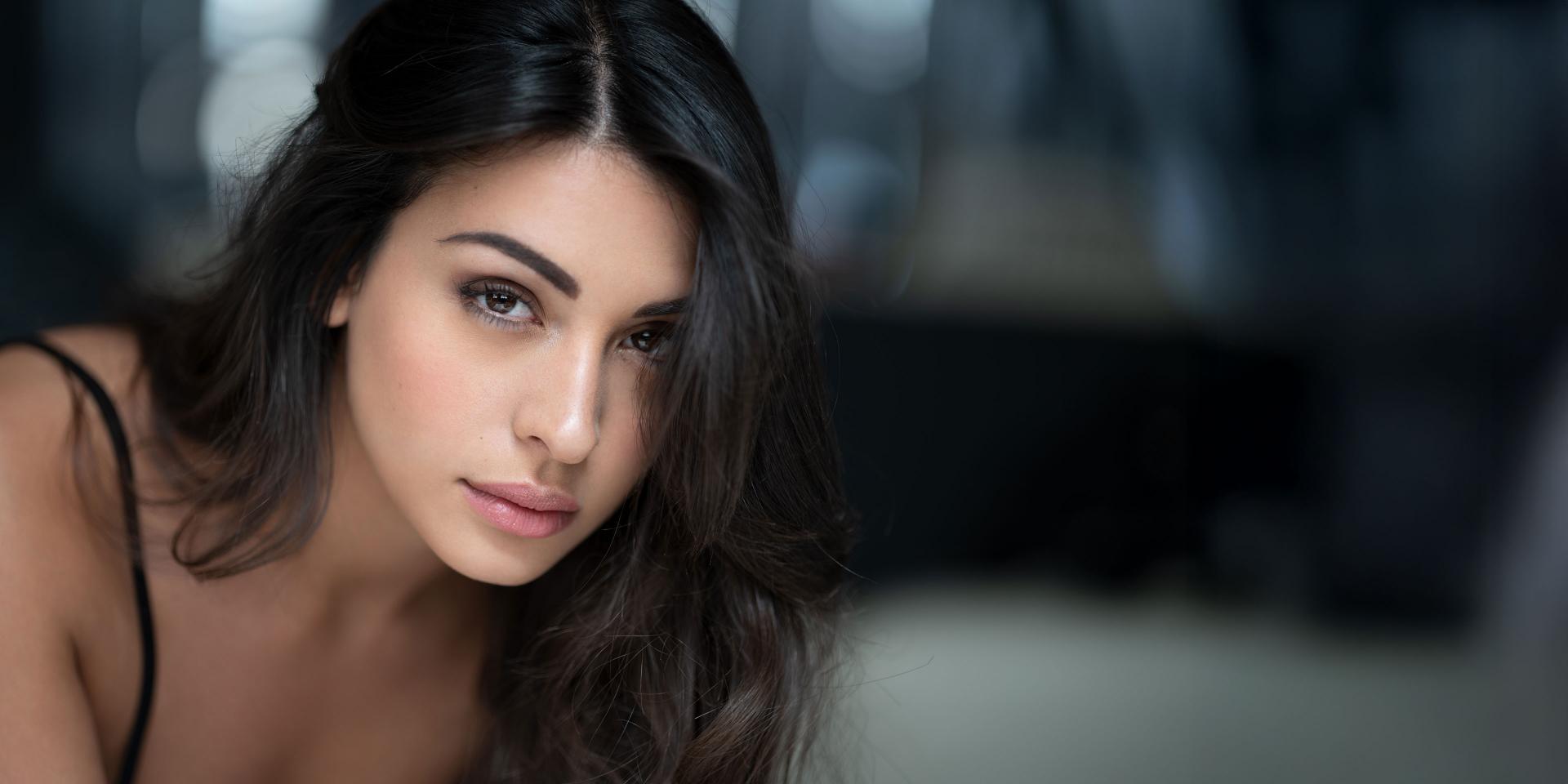 A close-up portrait of a woman with natural makeup and flowing hair, highlighting the lifelike skin tones and fine details captured by ZEISS optics.