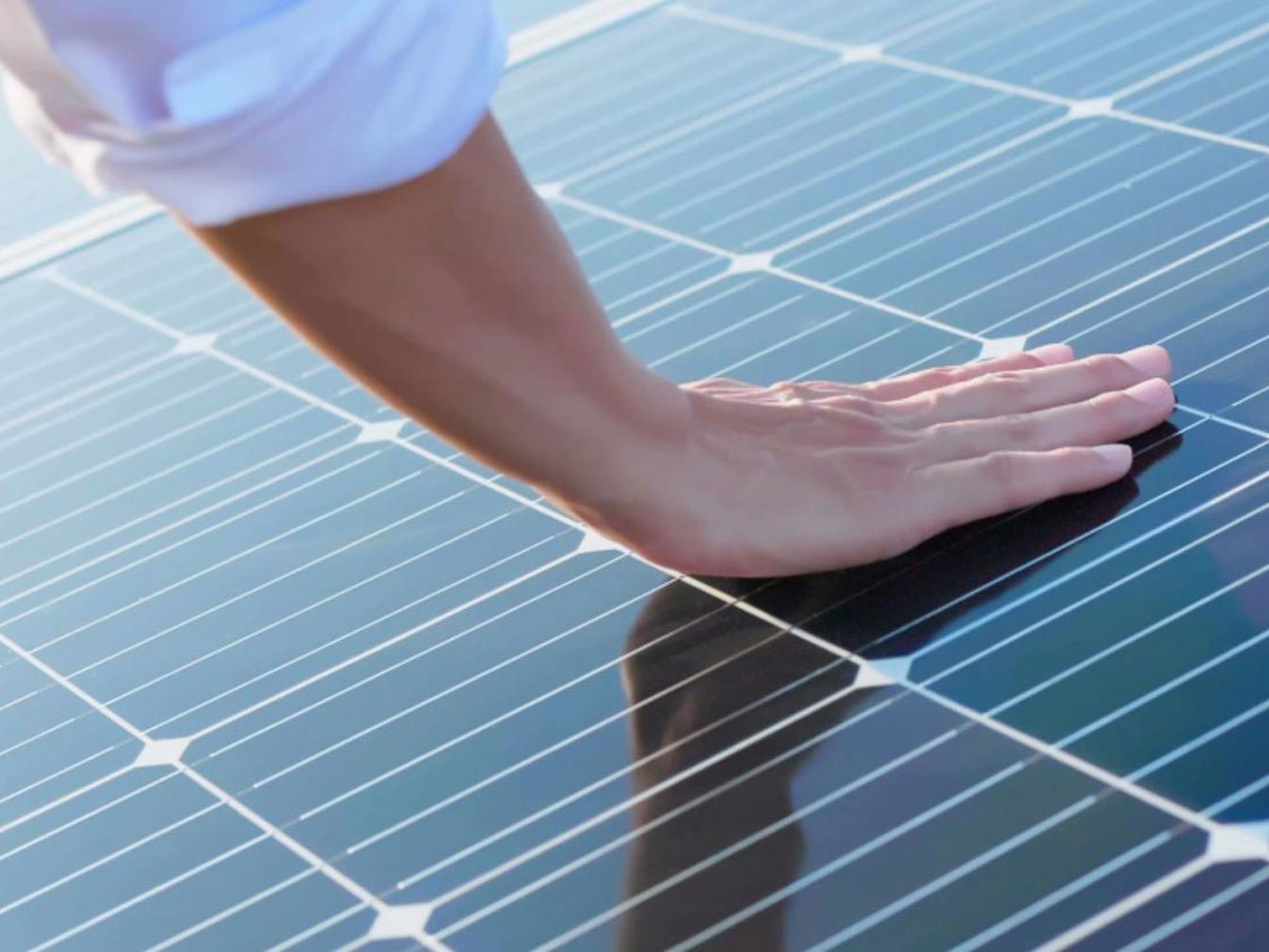 Una mano tocando módulos fotovoltaicos. 