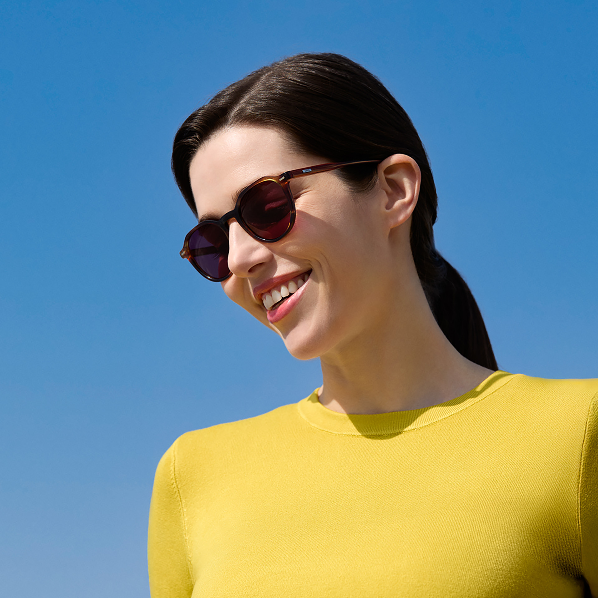 Una mujer con lentes de sol graduadas de ZEISS en color borgoña.