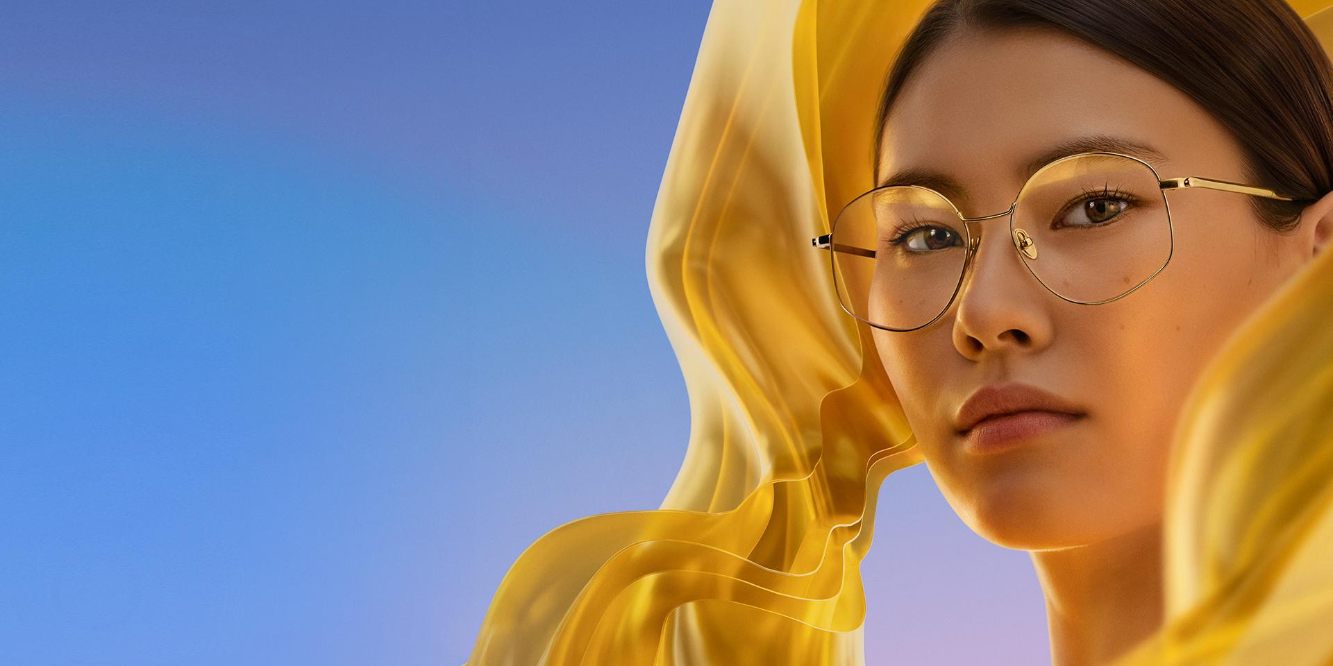 Una mujer con gafas transparentes con ZEISS DuraVision Gold UV, que añade un sutil reflejo dorado a las lentes.