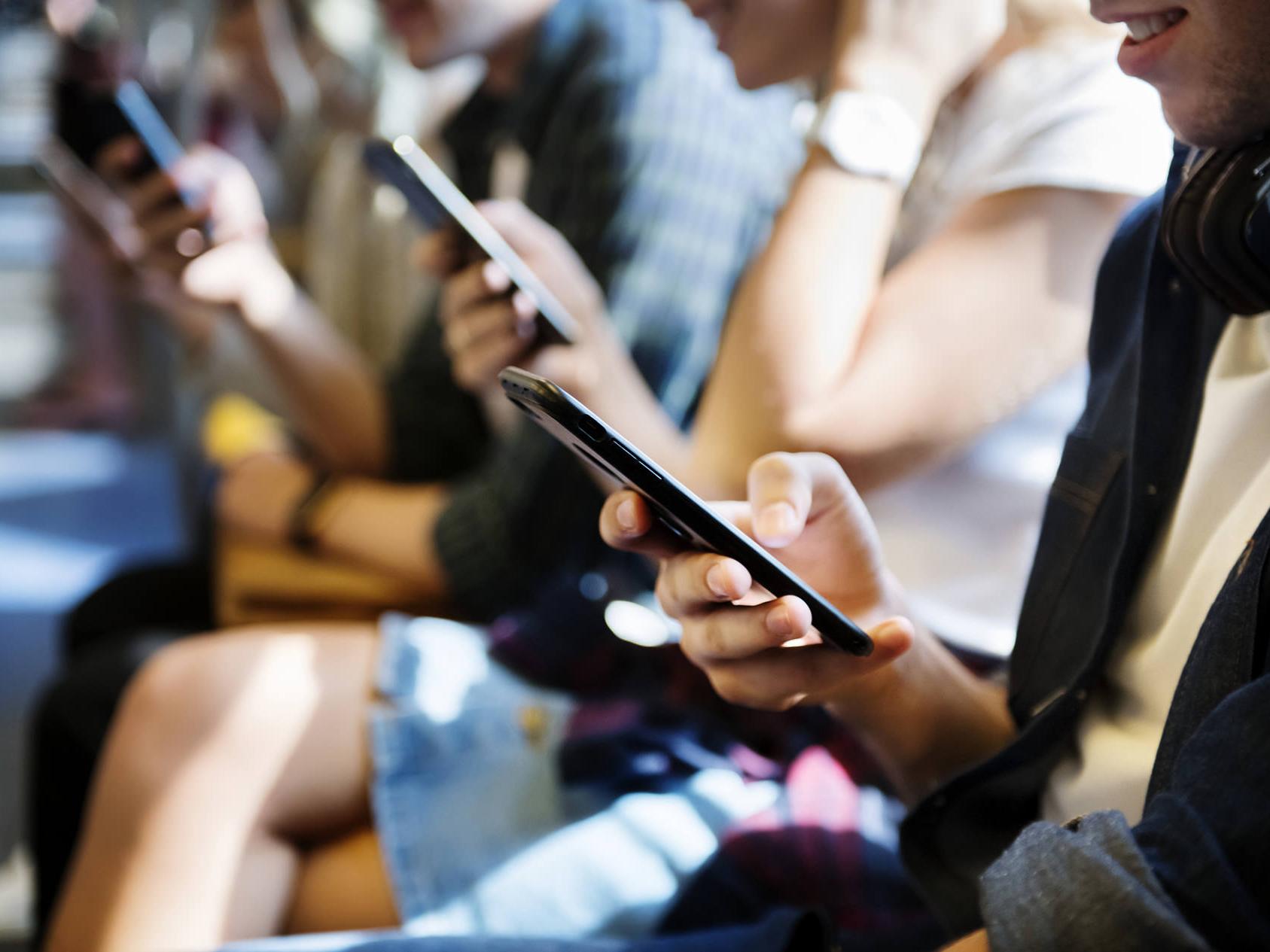 Los teléfonos inteligentes emiten niveles altos de luz azul. Imagen con muchas personas mirando sus smartphones. 