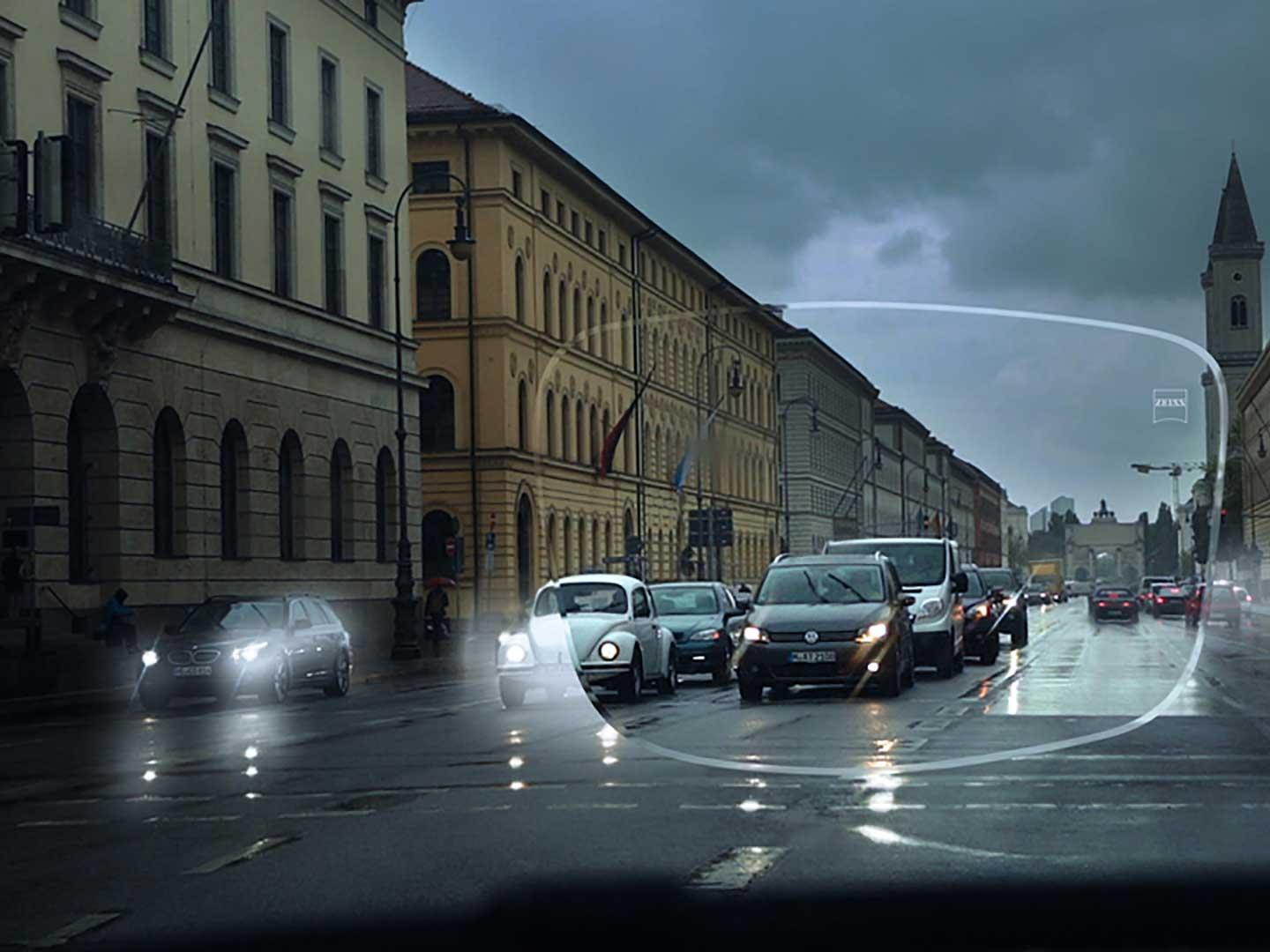 La imagen muestra una calle con escasa visibilidad por condiciones de poca luz. Vista desde el interior de un vehículo a través de una lente para gafas. 
