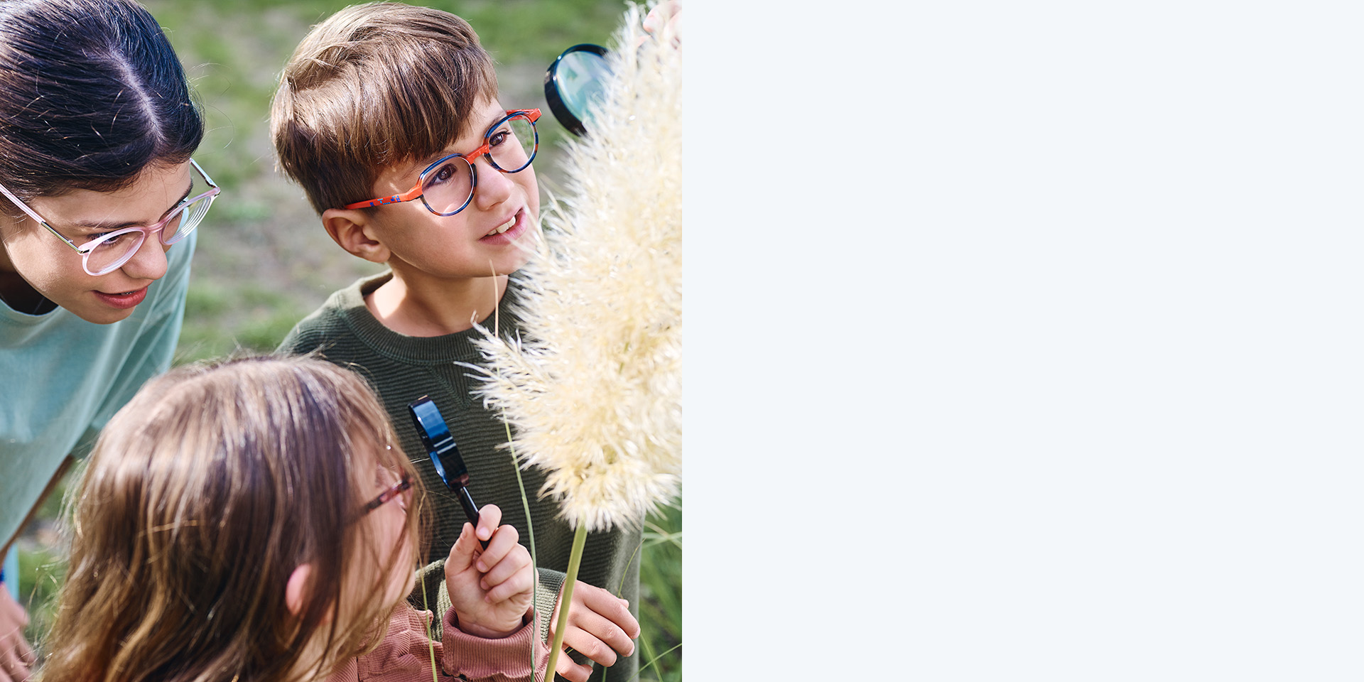 Dos niñas y un niño con lentes ZEISS MyoCare. Están mirando una planta, dos de los tres niños miran la planta usando lupas.