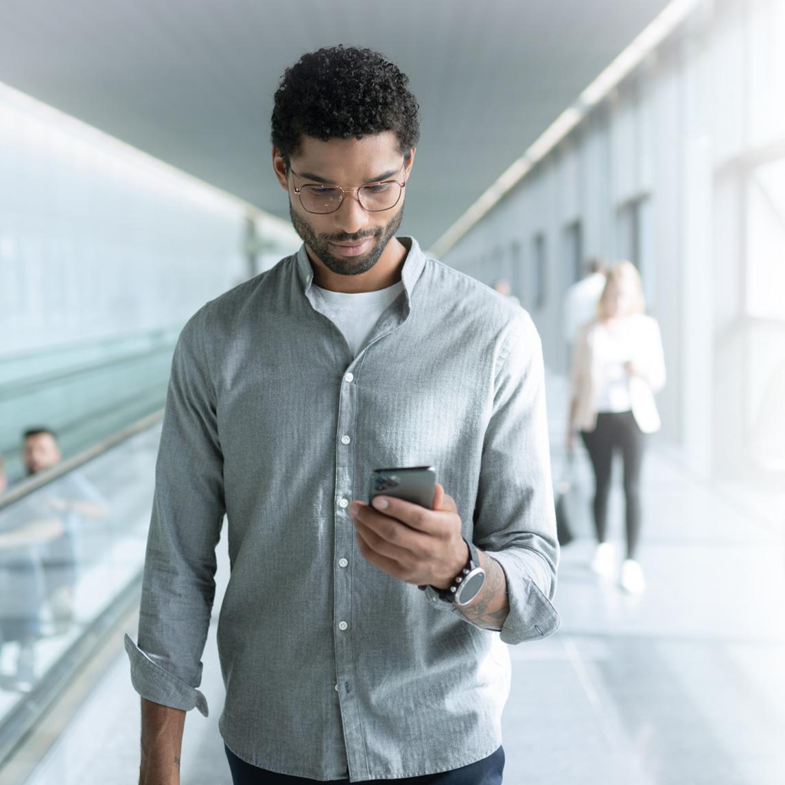 Un joven con las lentes ZEISS SmartLife consulta su teléfono mientras va andando.