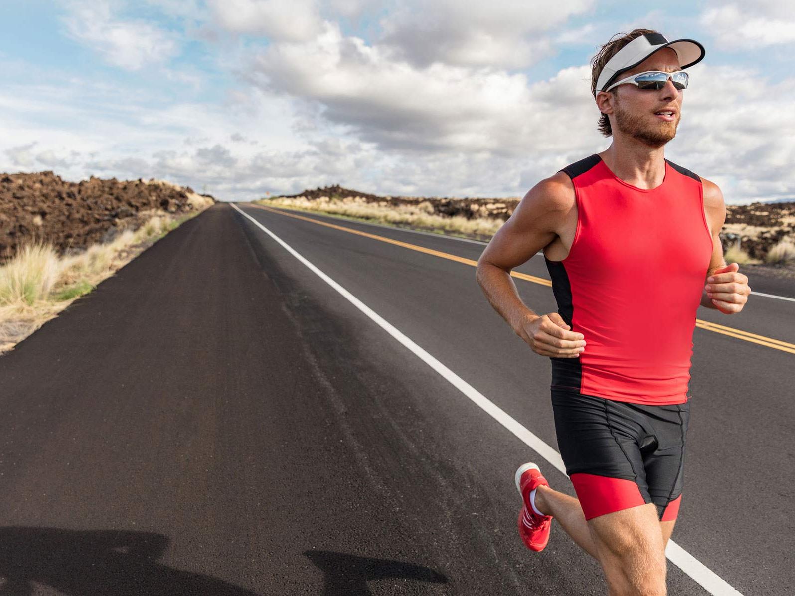 Imagen de un hombre con ropa deportiva y lentes deportivas mientras circula por una carretera. 