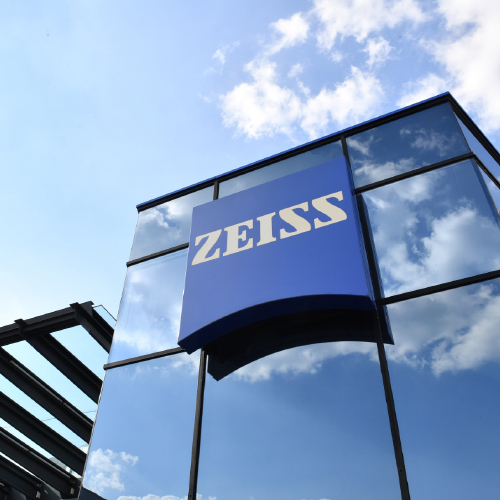Imagen de un moderno edificio de cristal con un gran logotipo de ZEISS. 