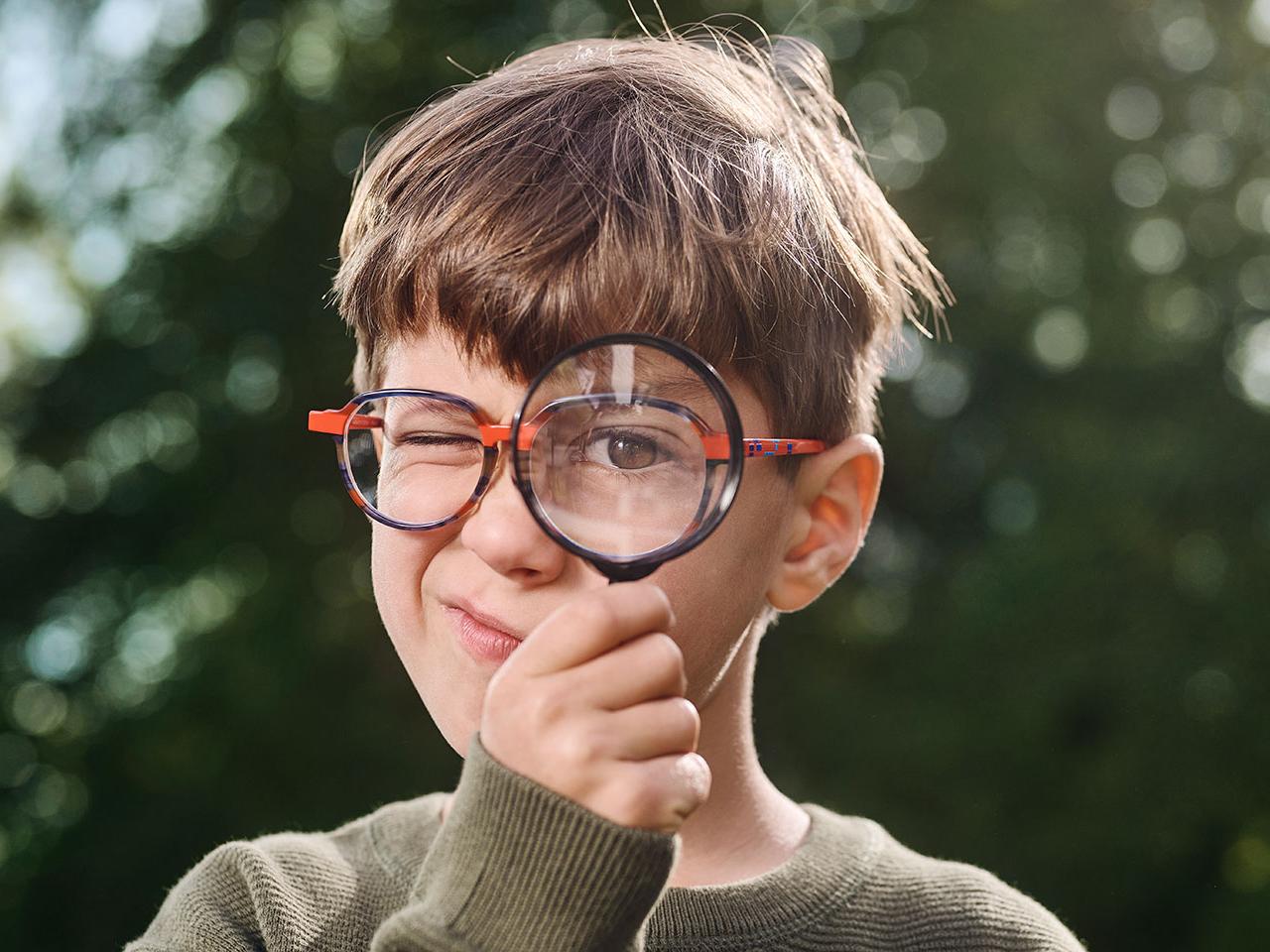 Niño con gafas usando una lupa 