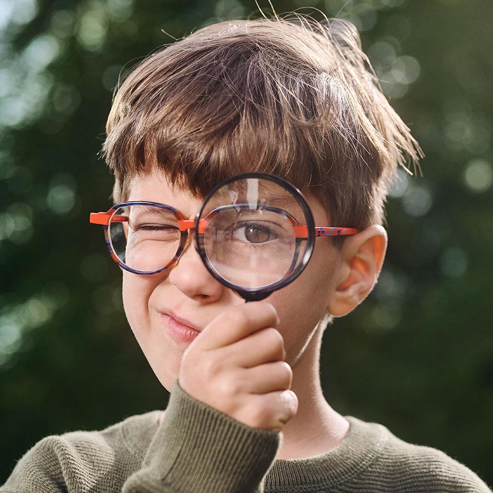 Niño con gafas usando una lupa 