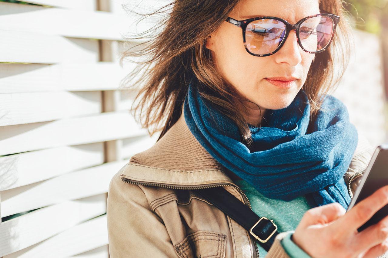 Mujer con un café en la mano y usando el teléfono