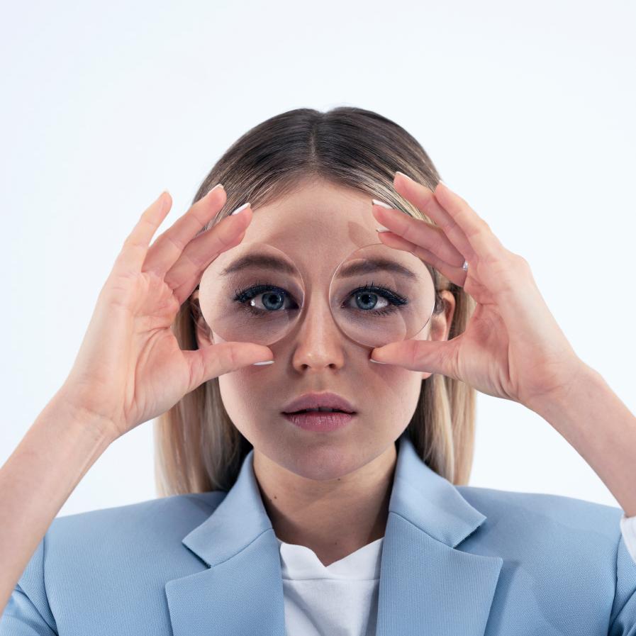 Una joven sostiene dos lentes gruesas delante de los ojos para mostrar el efecto pecera.