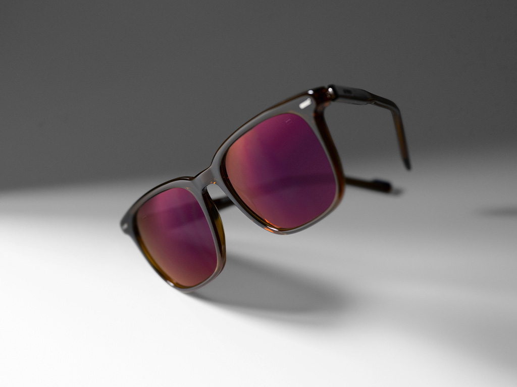 Imagen de unos cristales para gafas de sol graduadas ZEISS con lentes tintadas en color burdeos y recubrimiento de lentes ZEISS DuraVision Gold.