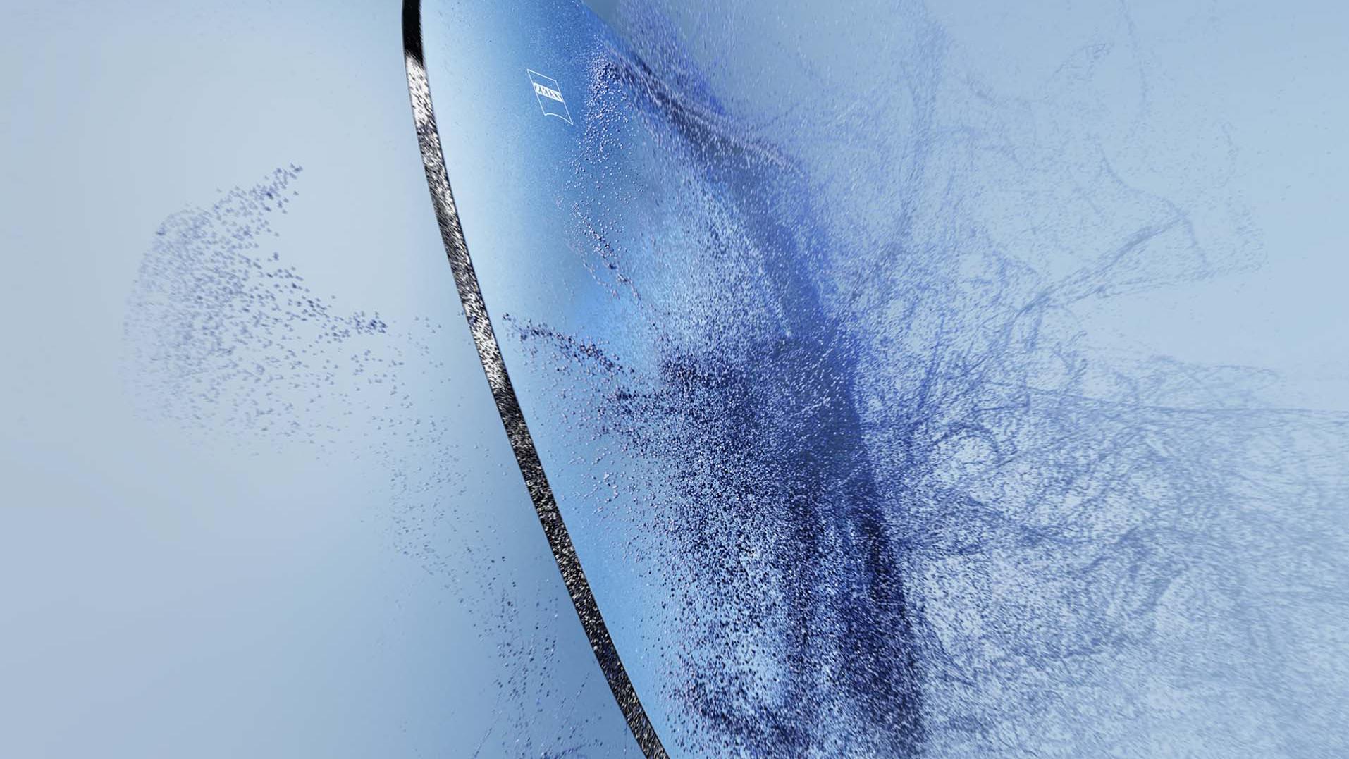 Arena impacta sobre una lente para gafas con el logotipo de ZEISS.