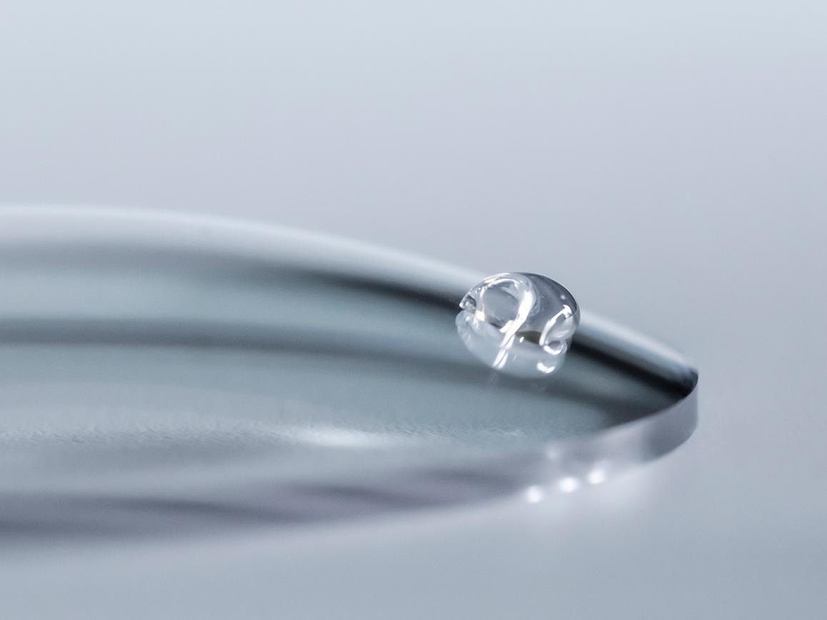 Una gota de agua se desliza por una lente ZEISS con un protector de limpieza fácil.