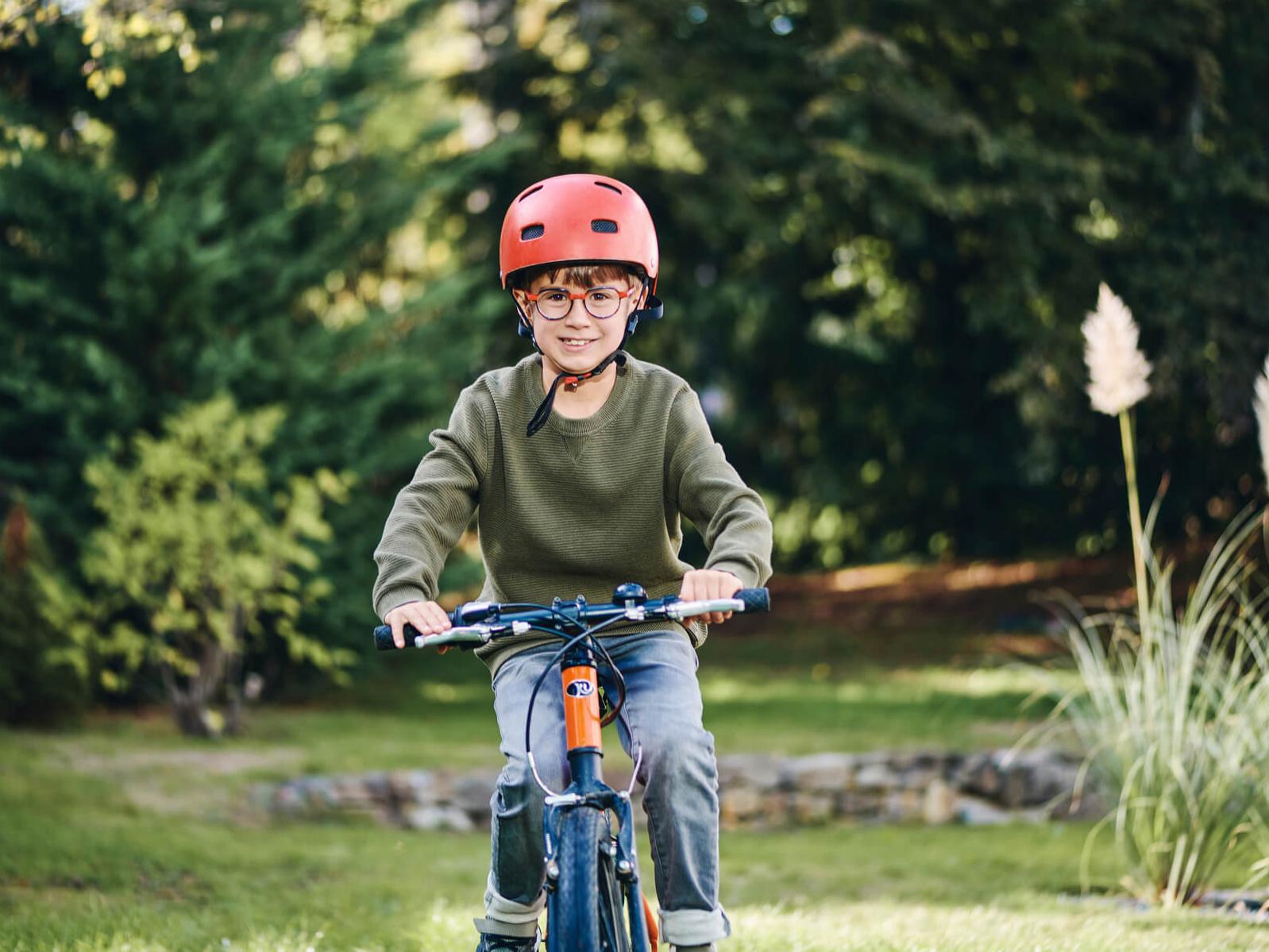 Un niño con lentes para el control de la miopía ZEISS sobre una bicicleta al aire libre.