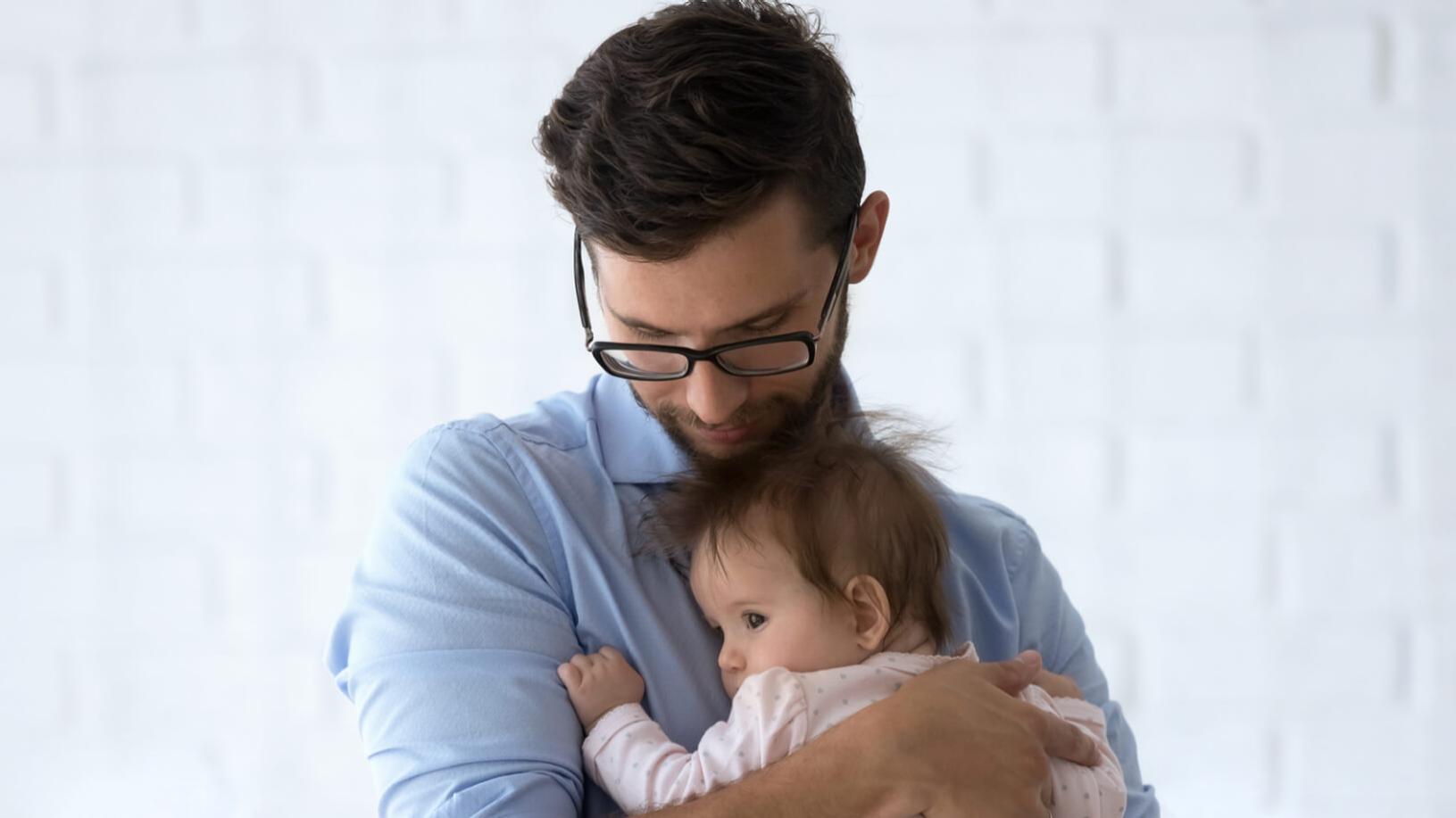 Un hombre miope con gafas sujetando a un niño pequeño.