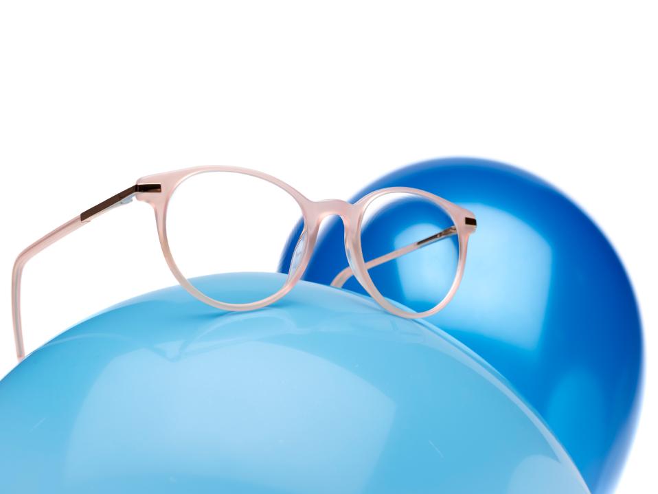 Montura de gafas rosa con lentes ZEISS MyoCare en un globo azul.