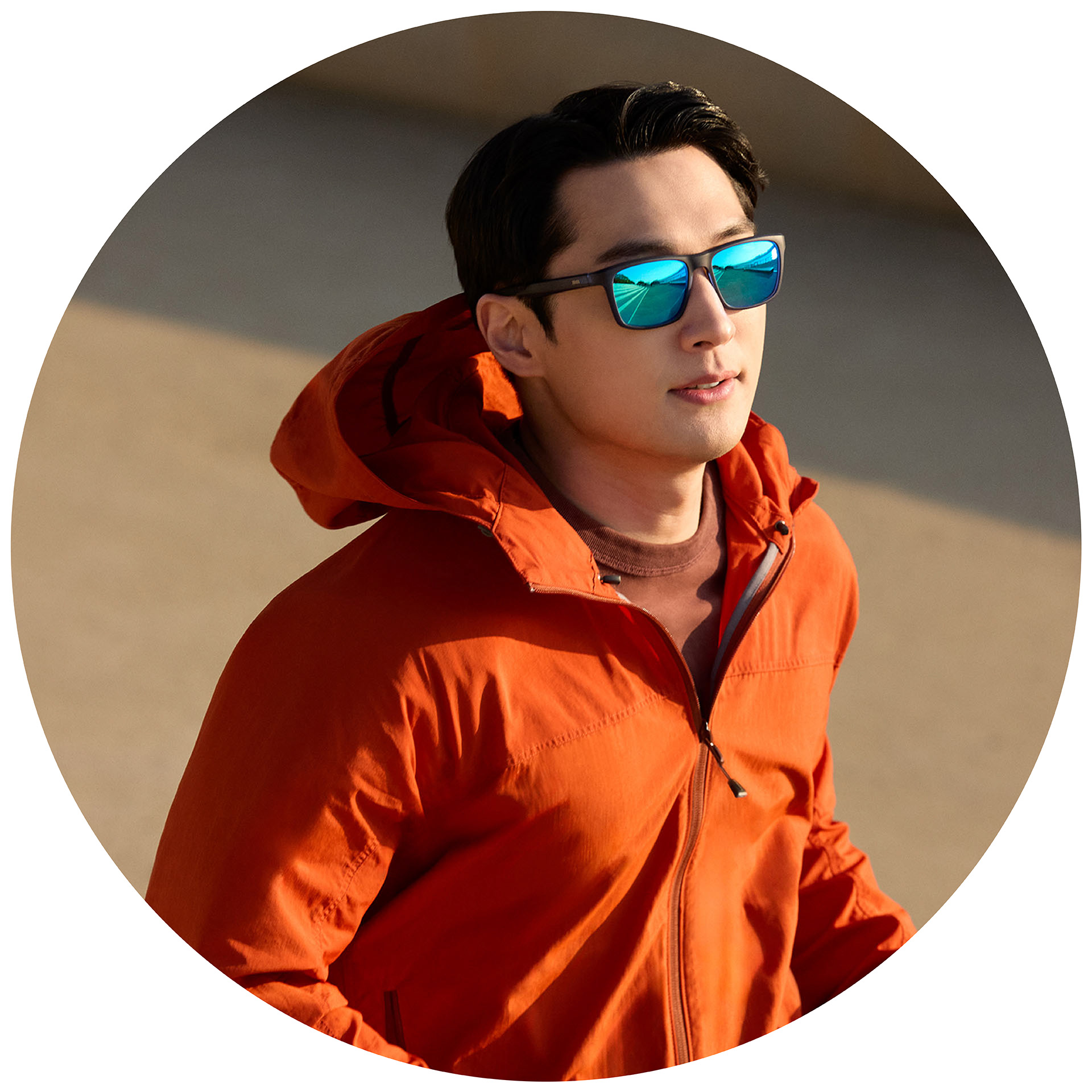 Una persona corriendo con una chaqueta naranja y gafas de sol graduadas ZEISS con protector espejado azul.