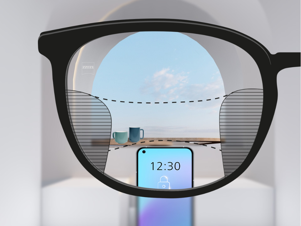 Una imagen con lentes progresivas ZEISS SmartLife con un móvil y copas al fondo, mientras la lente está totalmente despejada con zonas borrosas a izquierda y derecha.