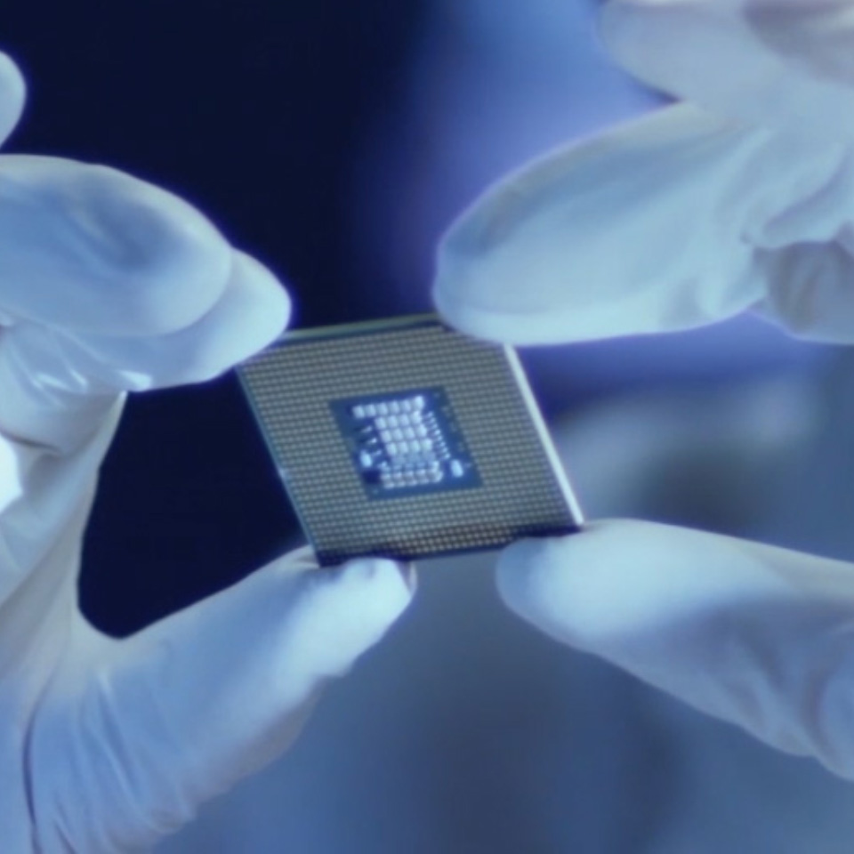 Imagen de un microchip sostenido por una persona con guantes de laboratorio. 